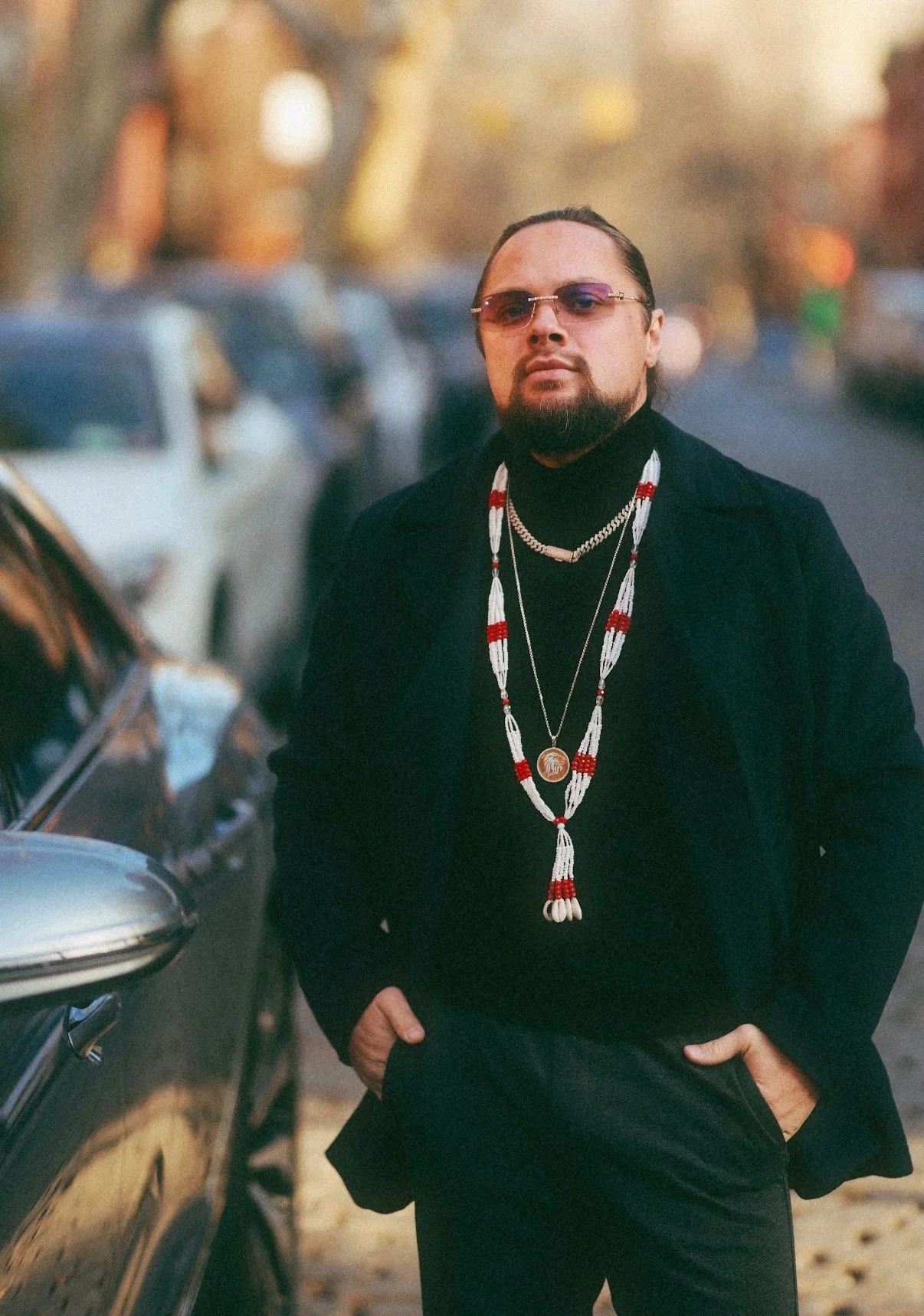 Mark Pugachev wearing a dark coat beside a car